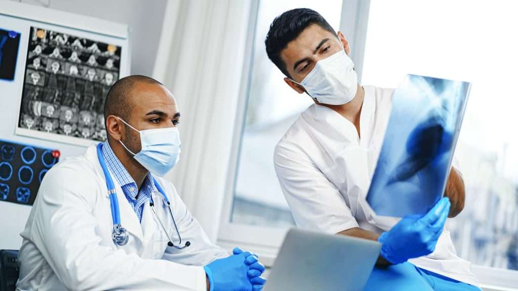 dos médicos varones examinan la resonancia magnética cerebral de una paciente