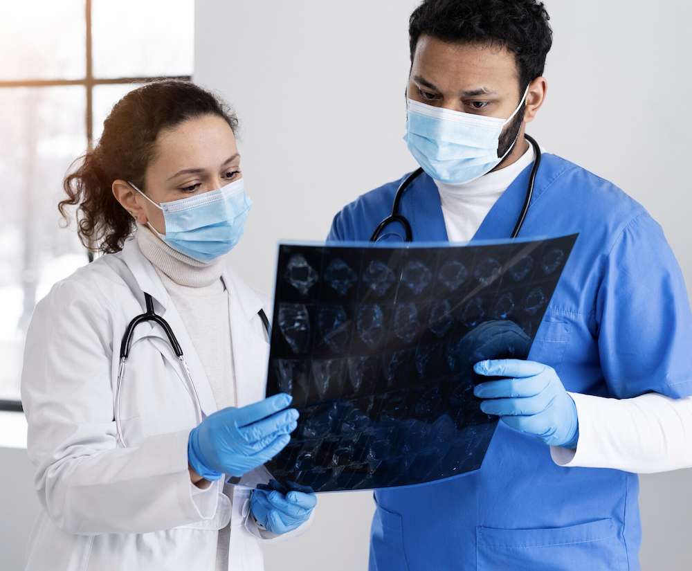 Plano medio médico y enfermera mirando radiografía